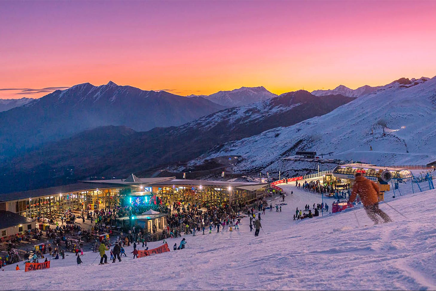 Coronet Peak is seen at dusk under a wonderful pink sky with mountains in the background.